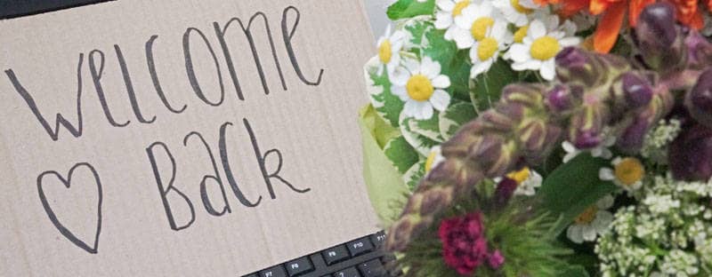 Welcome Back Schild auf Tastatur mit Blumenstrauß