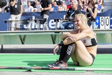 Stefanie Dauber sitzt nach erfolgreichem Sprung fröhlich auf dem Boden.