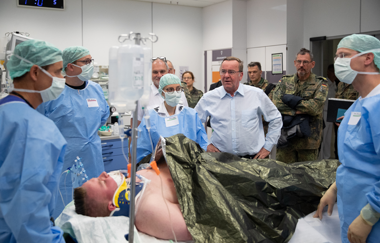 Boris Pistorius lässt sich in einem Krankenzimmer von Ärztinnen und Ärzten die Behandlung eines Probe-Patienten erläutern.